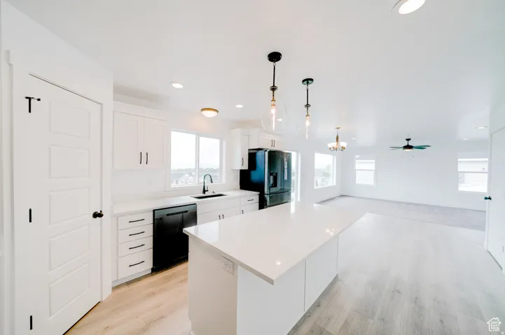 Kitchen featuring white cabinetry, a large center island, black appliances, and wood-finish flooring