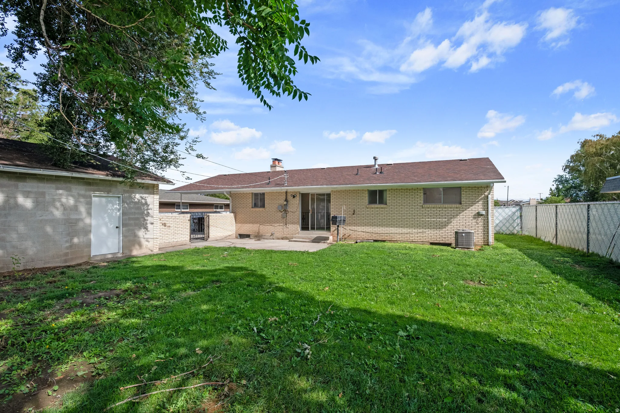 Expansive backyard featuring a manicured lawn, dedicated patio space, and a detached structure
