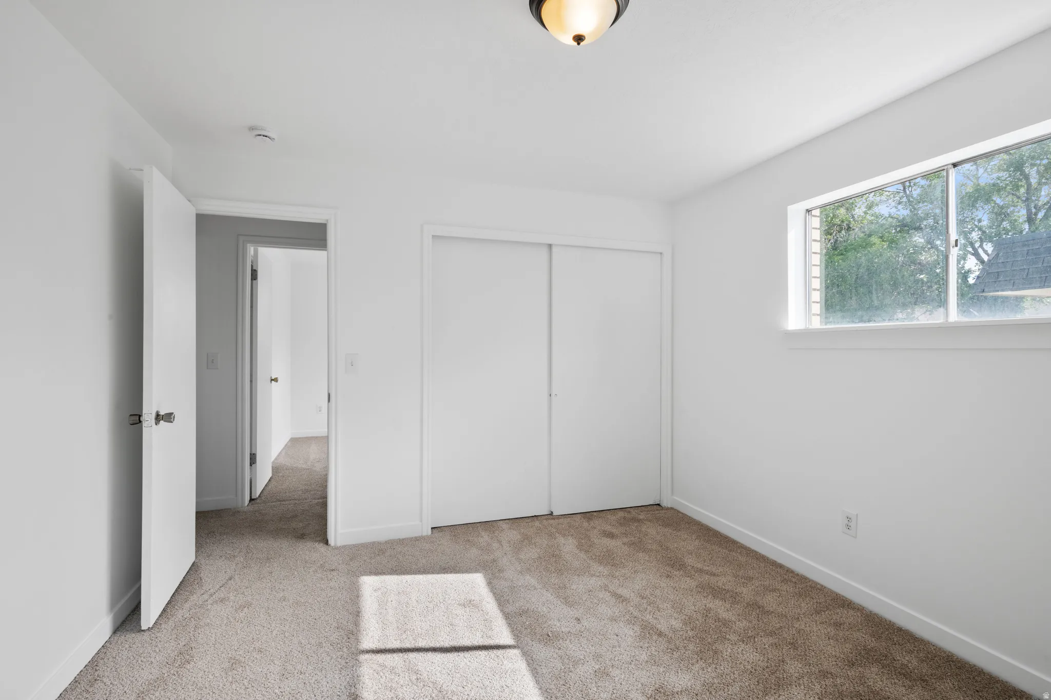 Plush carpet flooring, white walls, and a built-in closet with sliding doors