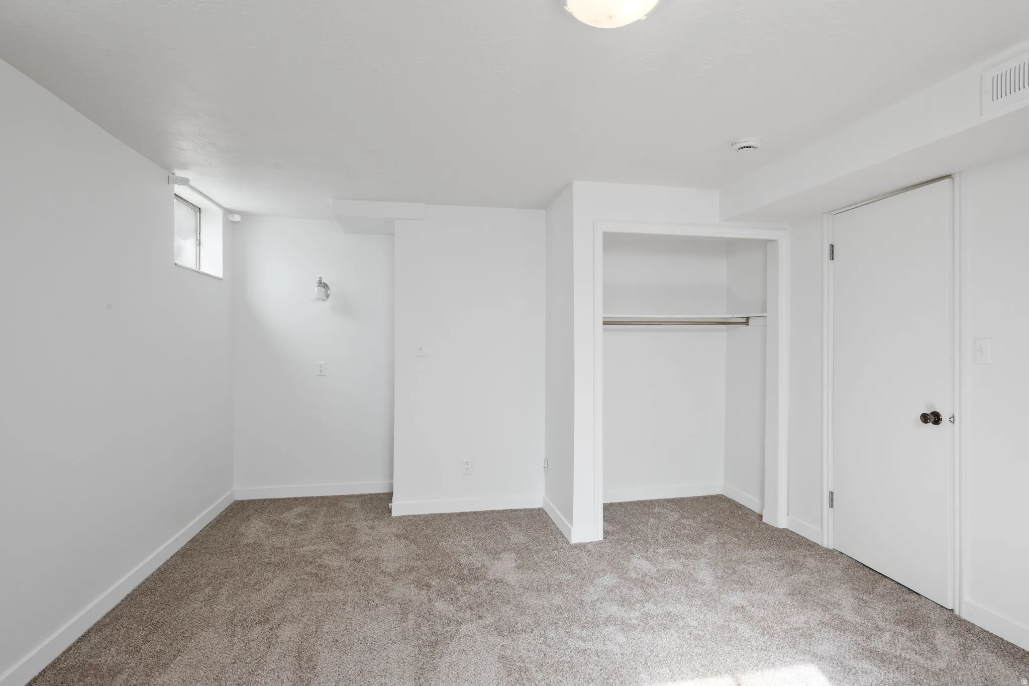 Neutral-toned carpeting, white painted walls, and built-in closet with shelving and hanging rod
