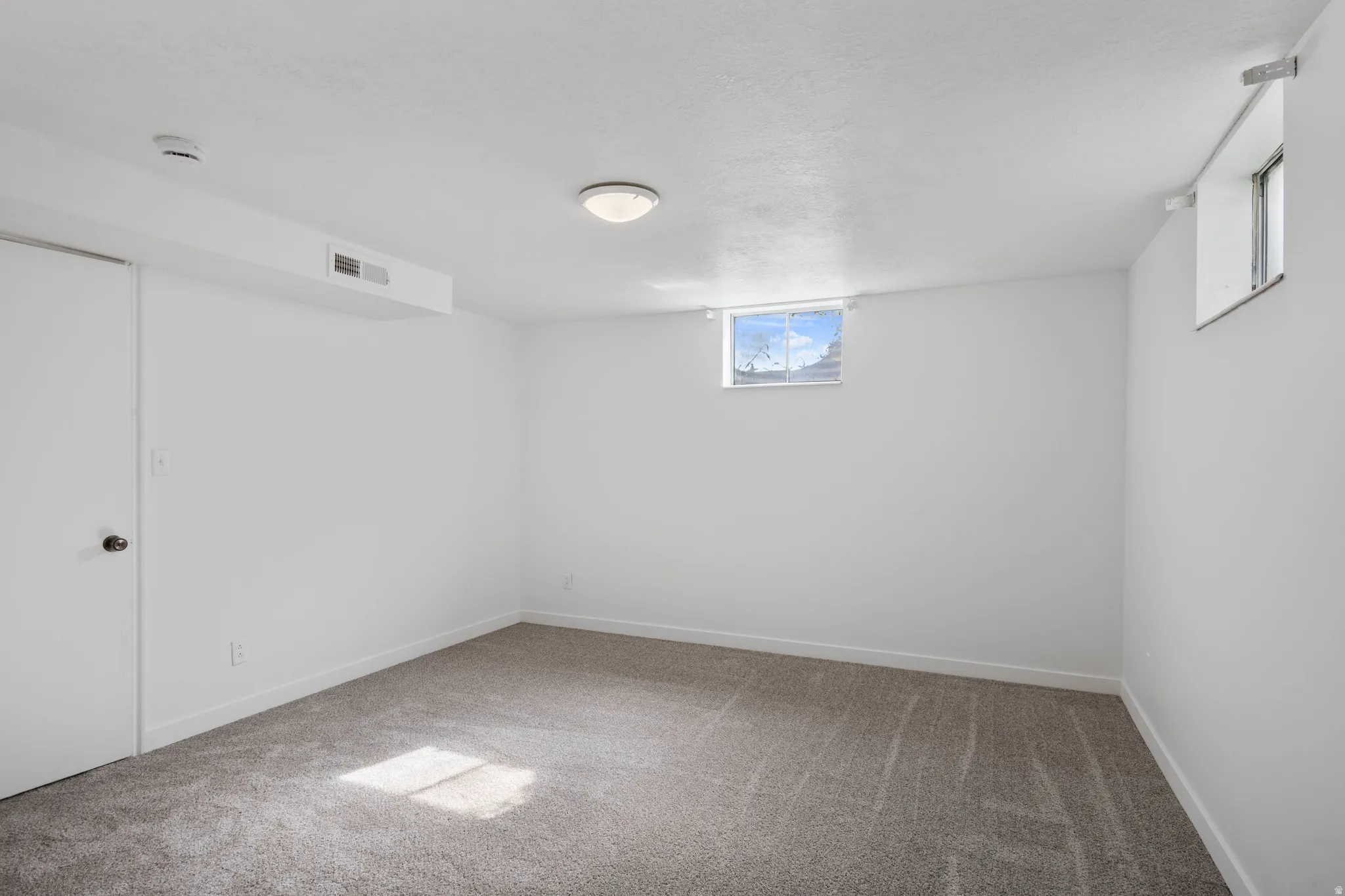 Carpeted flooring, white painted walls, and window