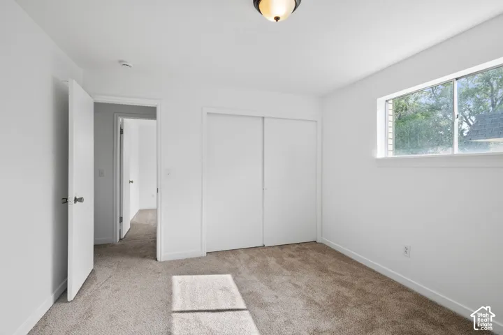 Plush carpet flooring, white walls, and a built-in closet with sliding doors