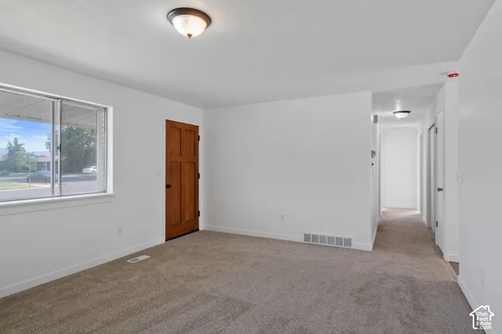 Neutral wall paint throughout, carpeted flooring, wood-paneled door, and recessed lighting