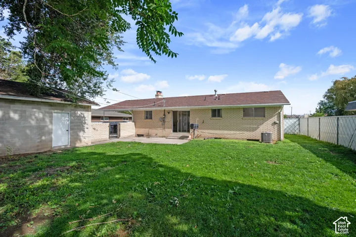 Expansive backyard featuring a manicured lawn, dedicated patio space, and a detached structure
