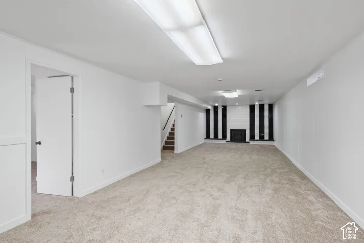 Expansive carpeted room featuring a fireplace with a black and white tiled surround and a black metal grate