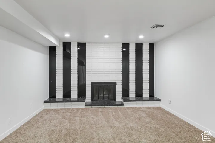 Brick fireplace with a black iron firebox, black granite hearth, and white tile surround