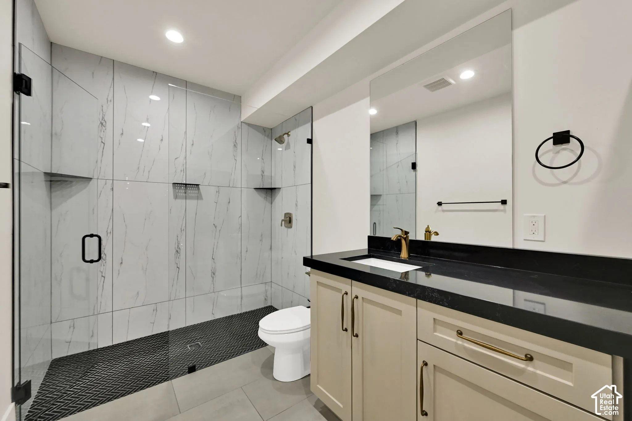 Glass-enclosed shower with white tiled walls and black mosaic floor