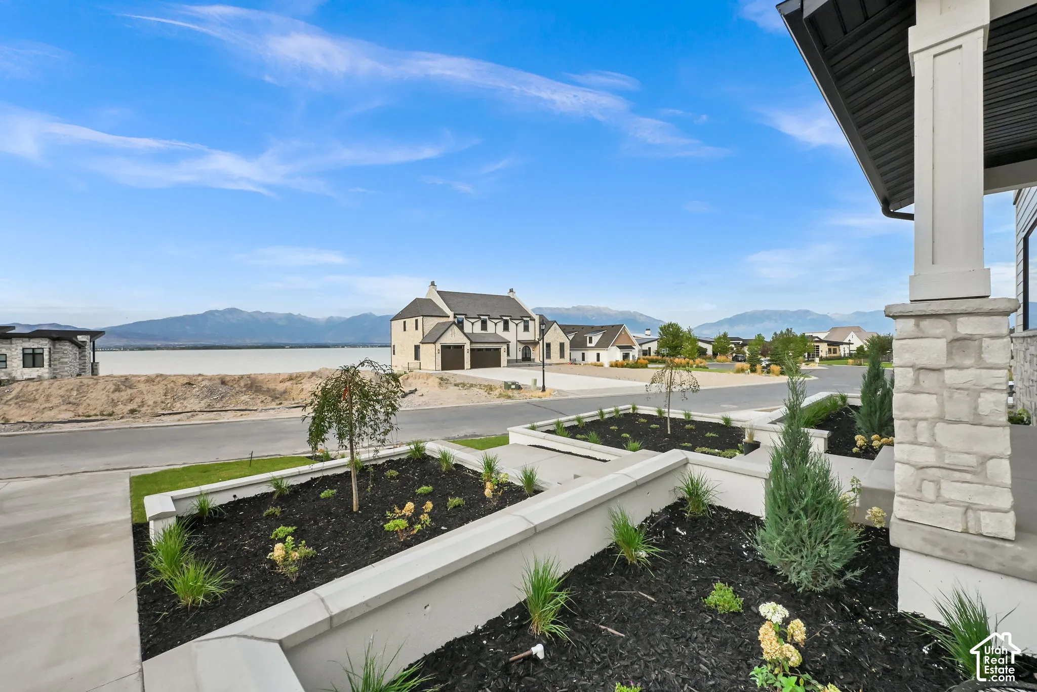 Expansive outdoor space featuring manicured landscaping, concrete pathways, and a stone facade column