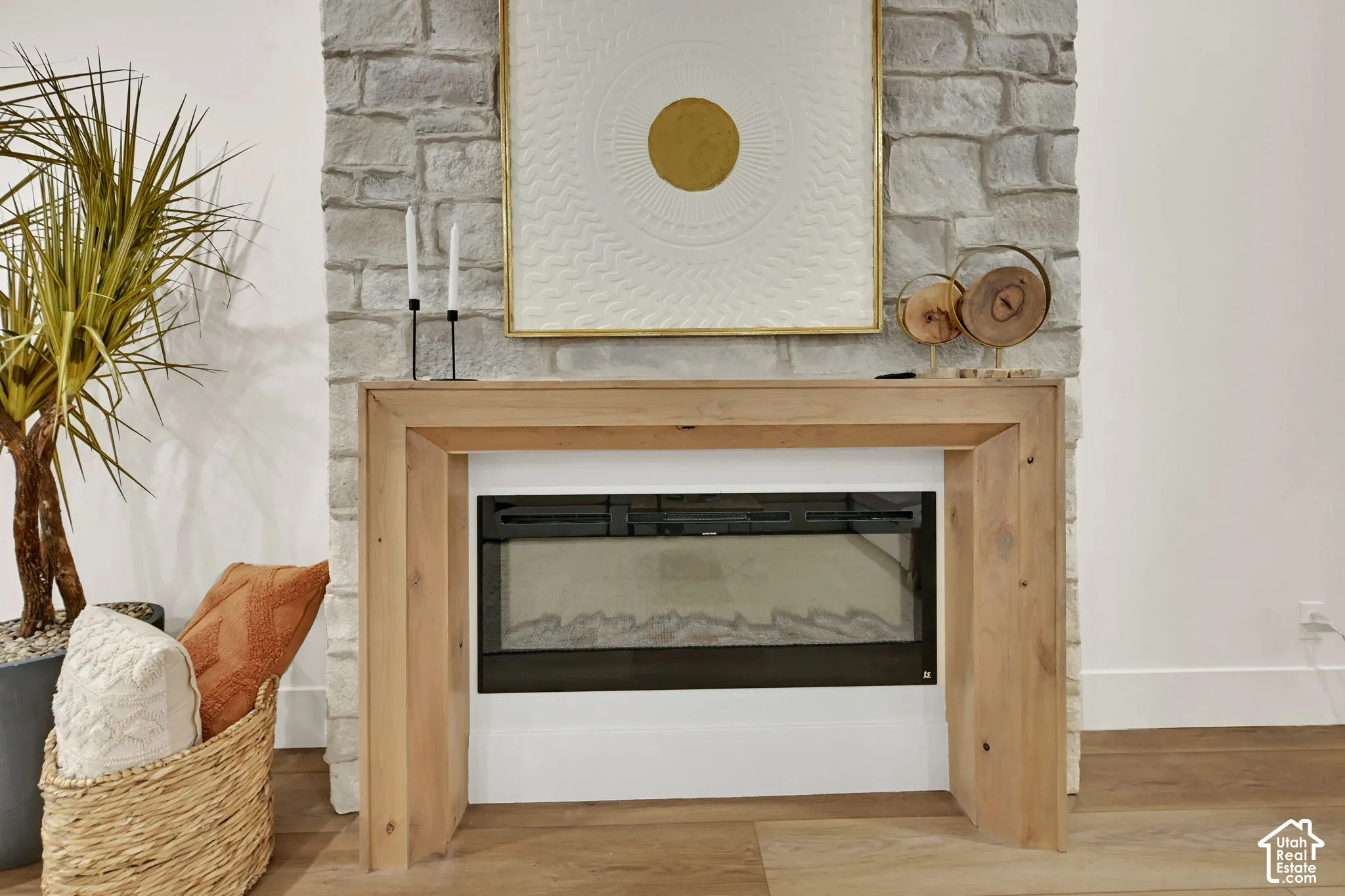 Stone accent wall featuring a built-in fireplace with a light wood mantle, set against light wood-finish flooring