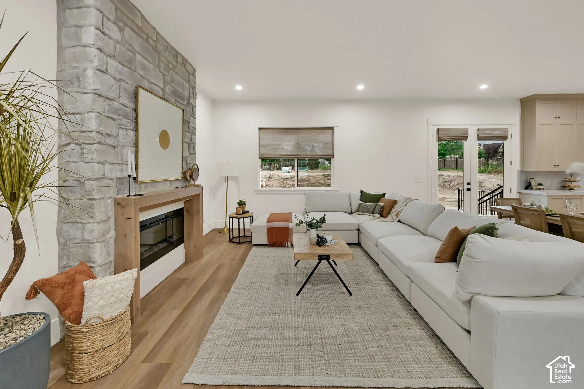 Stone-clad fireplace with a wood mantel, integrated electric fireplace, and wood-finish flooring