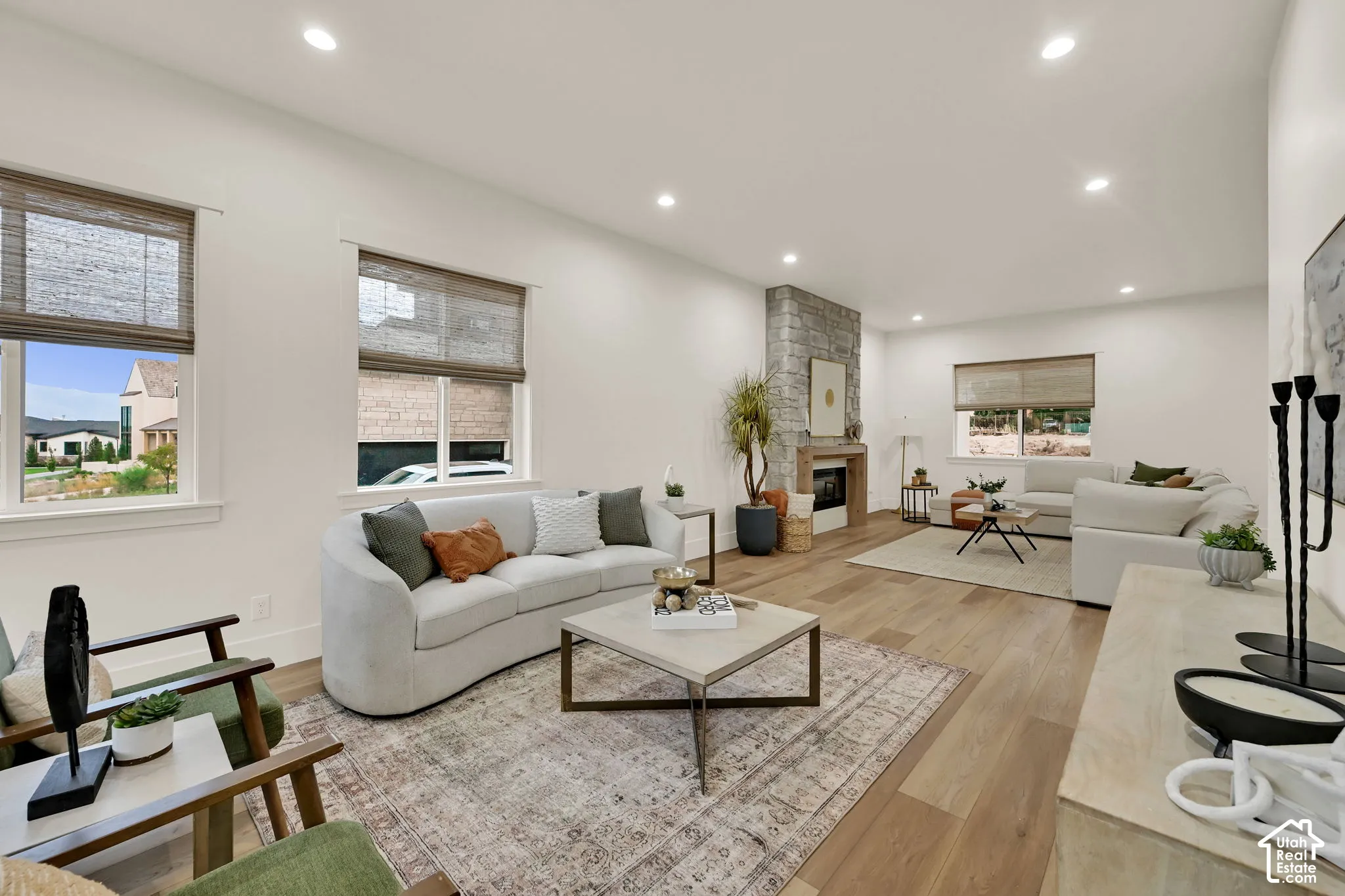 Wood-finish flooring, recessed lighting, and a stone-clad fireplace with a wood mantel