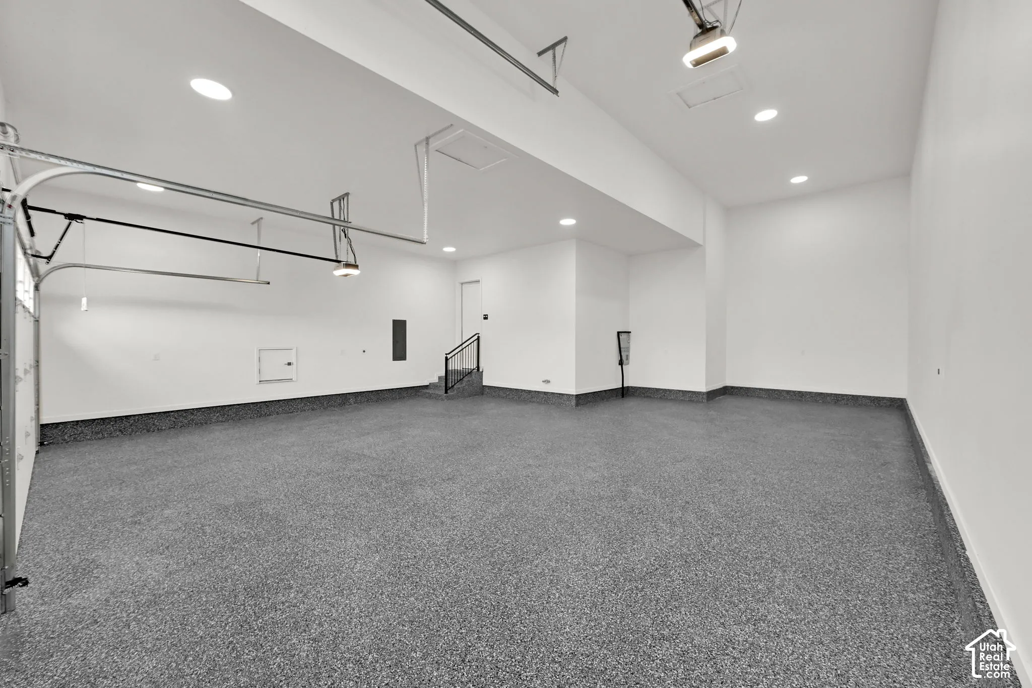 Spacious garage featuring a durable speckled epoxy floor, recessed lighting, and a utility access door