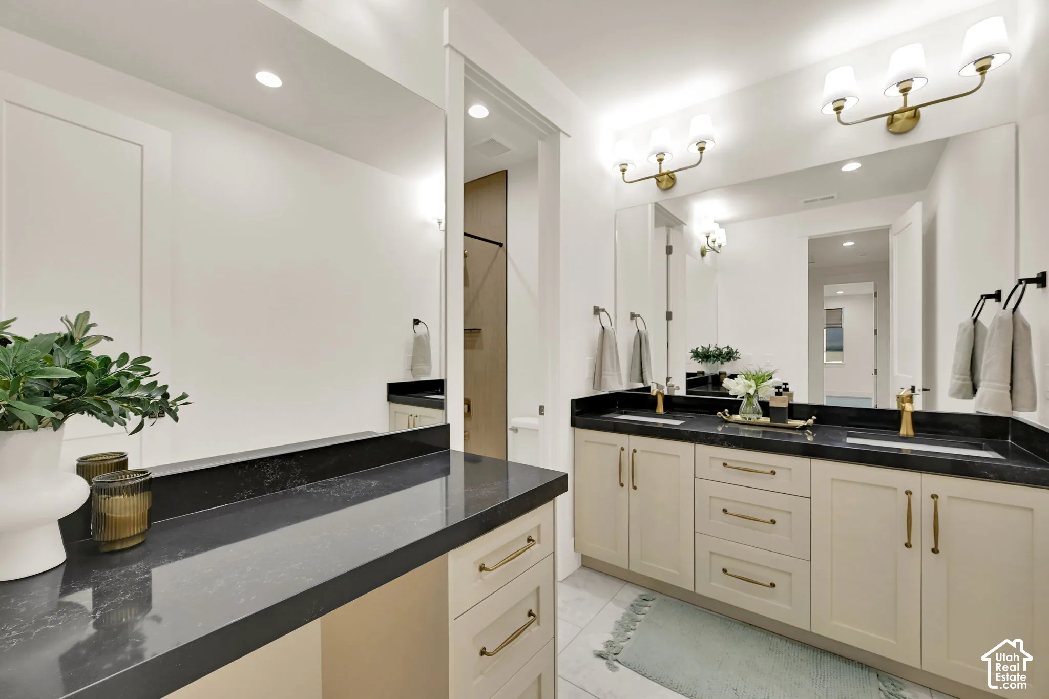 Dual vanity with undermount sinks, black countertops, and gold-finish fixtures