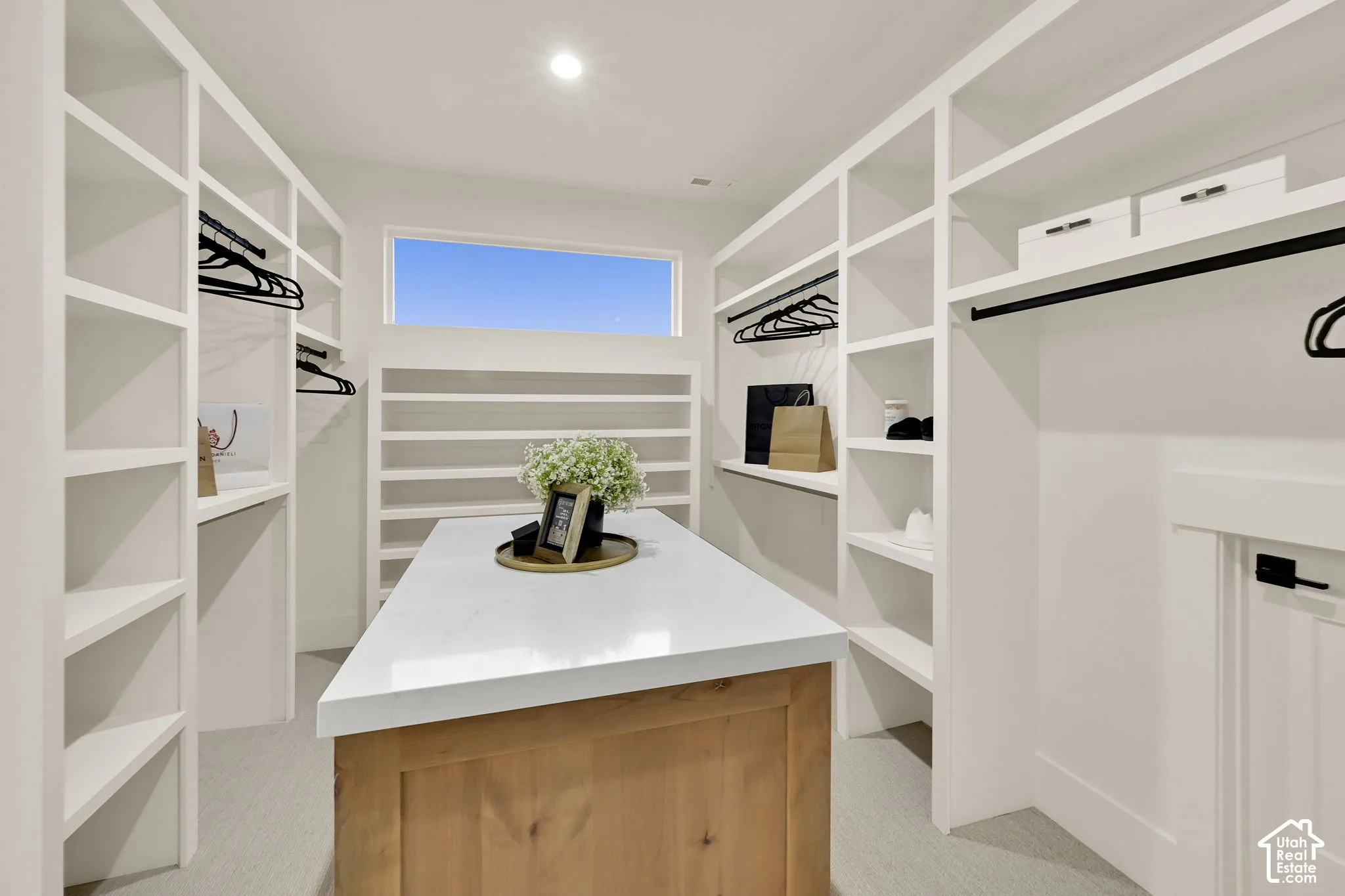 Custom closet system with extensive built-in shelving, hanging rods, and a central island featuring a light-toned countertop