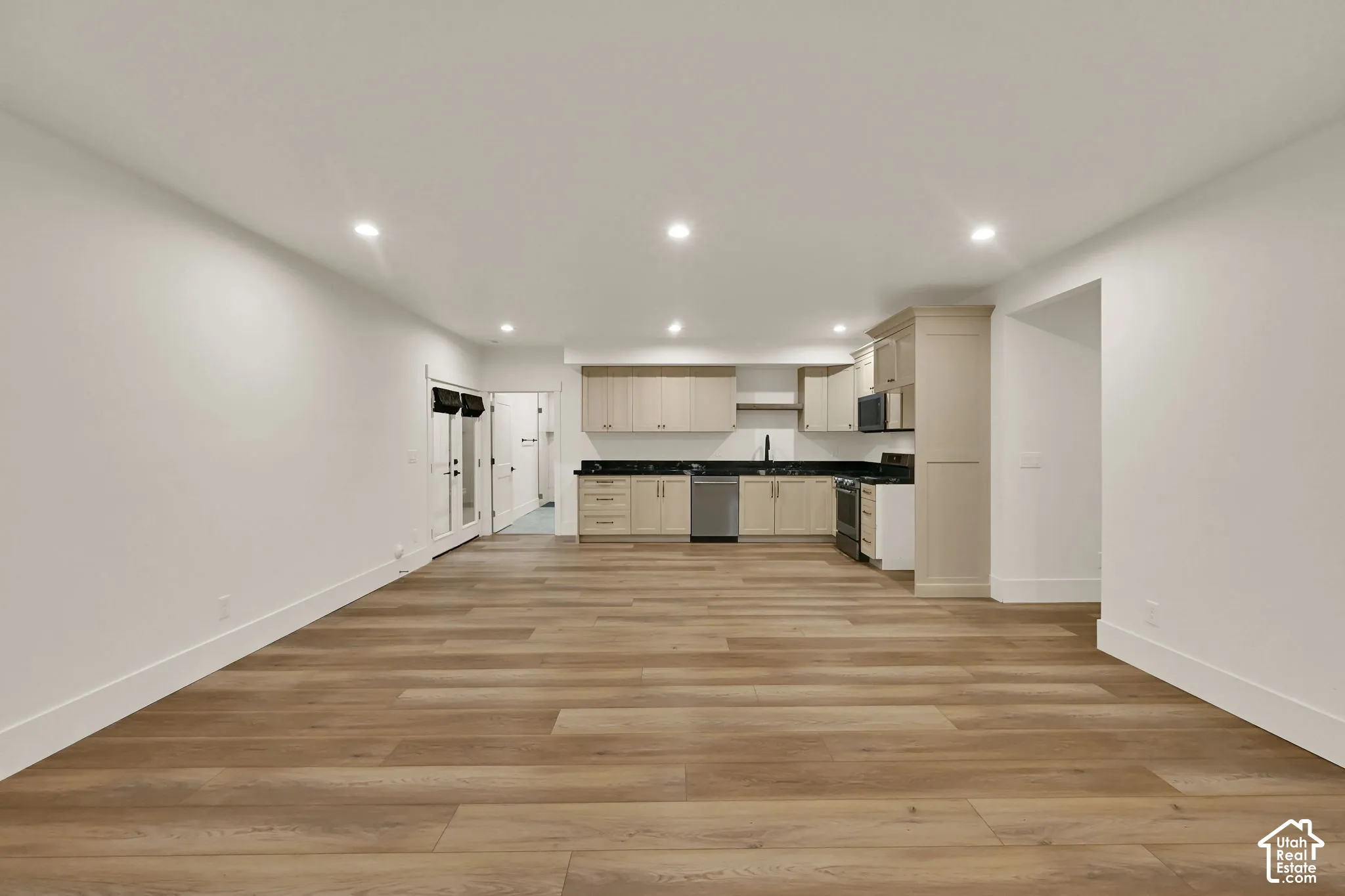 Recessed lighting, wood-finish flooring, light-toned cabinetry, dark countertops, and stainless steel appliances