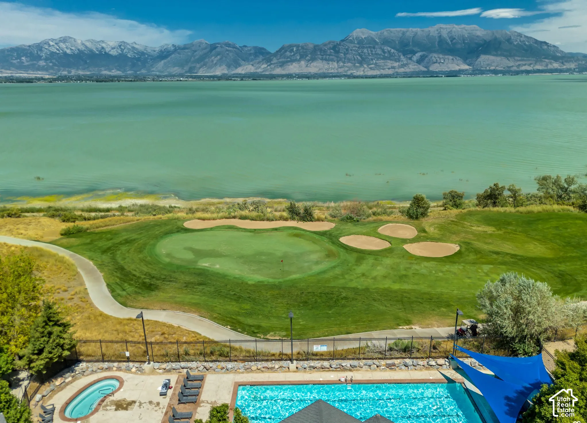 Championship golf course with manicured fairways and strategically placed bunkers overlooking turquoise waters and snow-capped mountain range