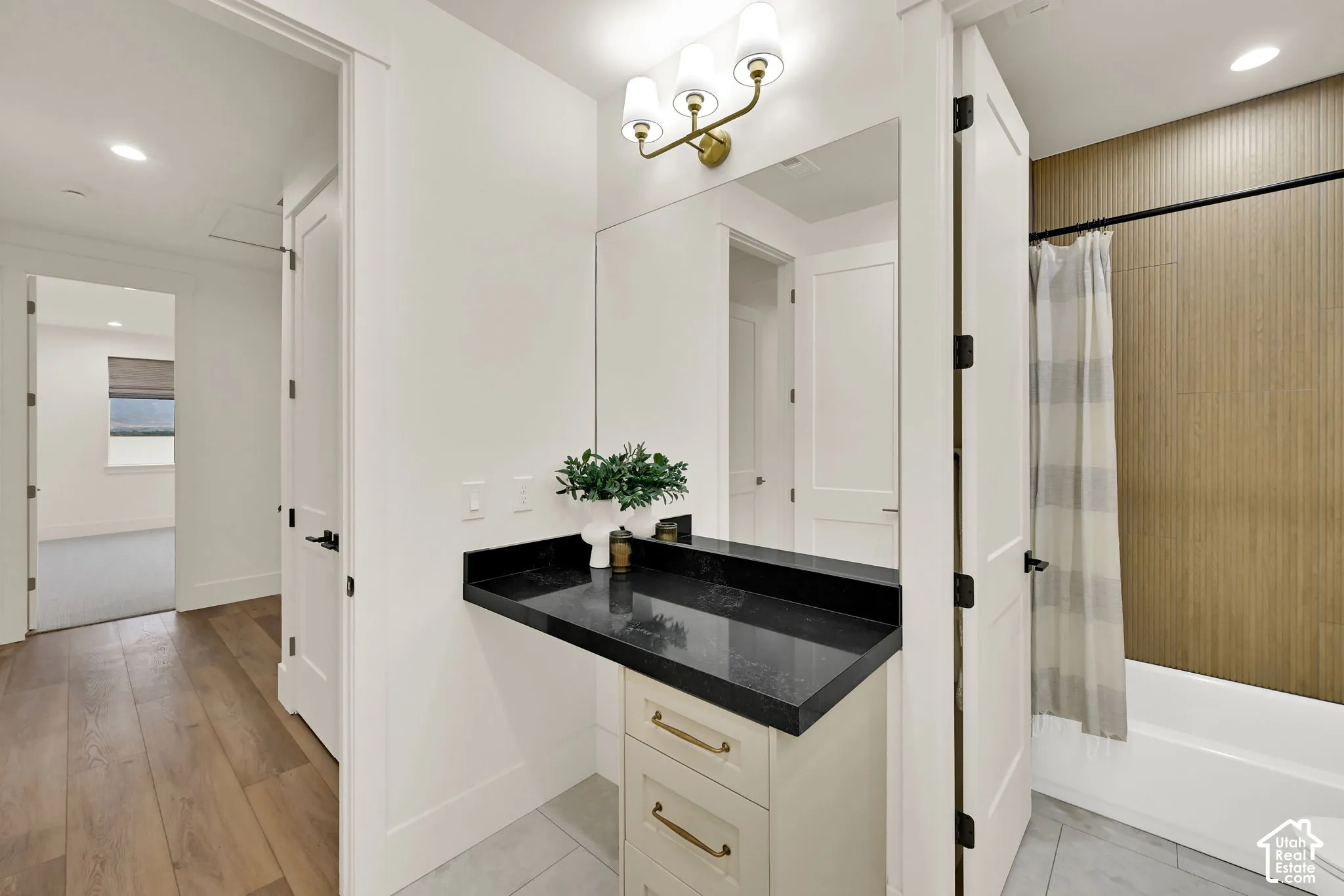 Built-in vanity with dark countertop, white cabinetry with gold-toned hardware, and a framed mirror