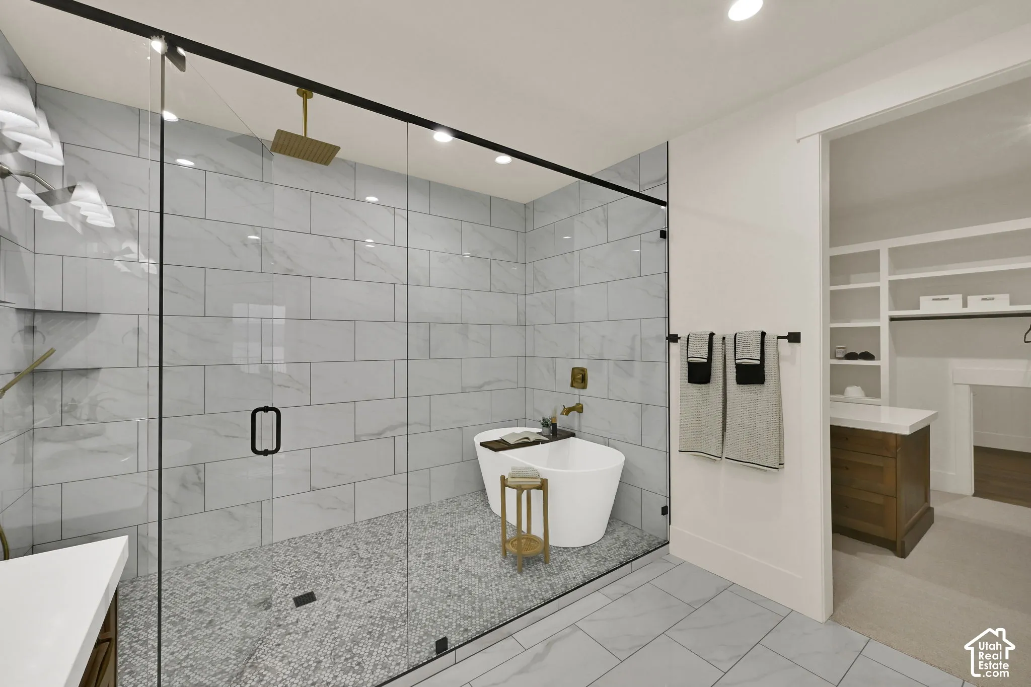 Glass-enclosed shower with subway tile walls and pebble flooring, featuring a freestanding tub and a rainfall showerhead