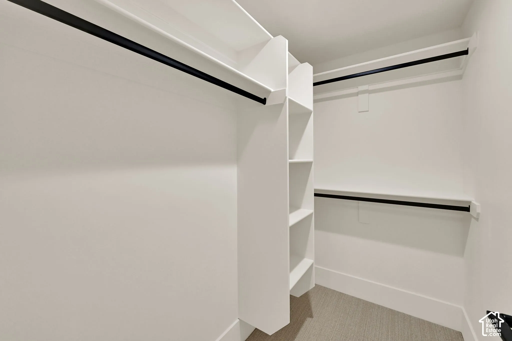 Built-in closet system with shelving, black hanging rods, and light-colored carpeting