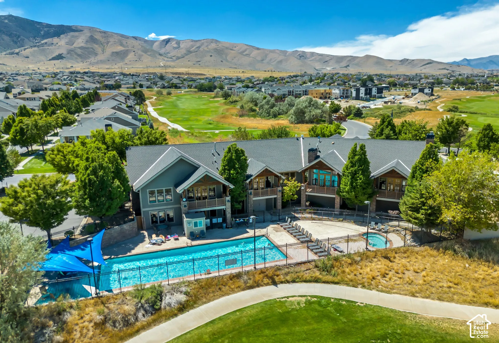Community amenity building with an outdoor swimming pool, hot tub, and surrounding paved patio