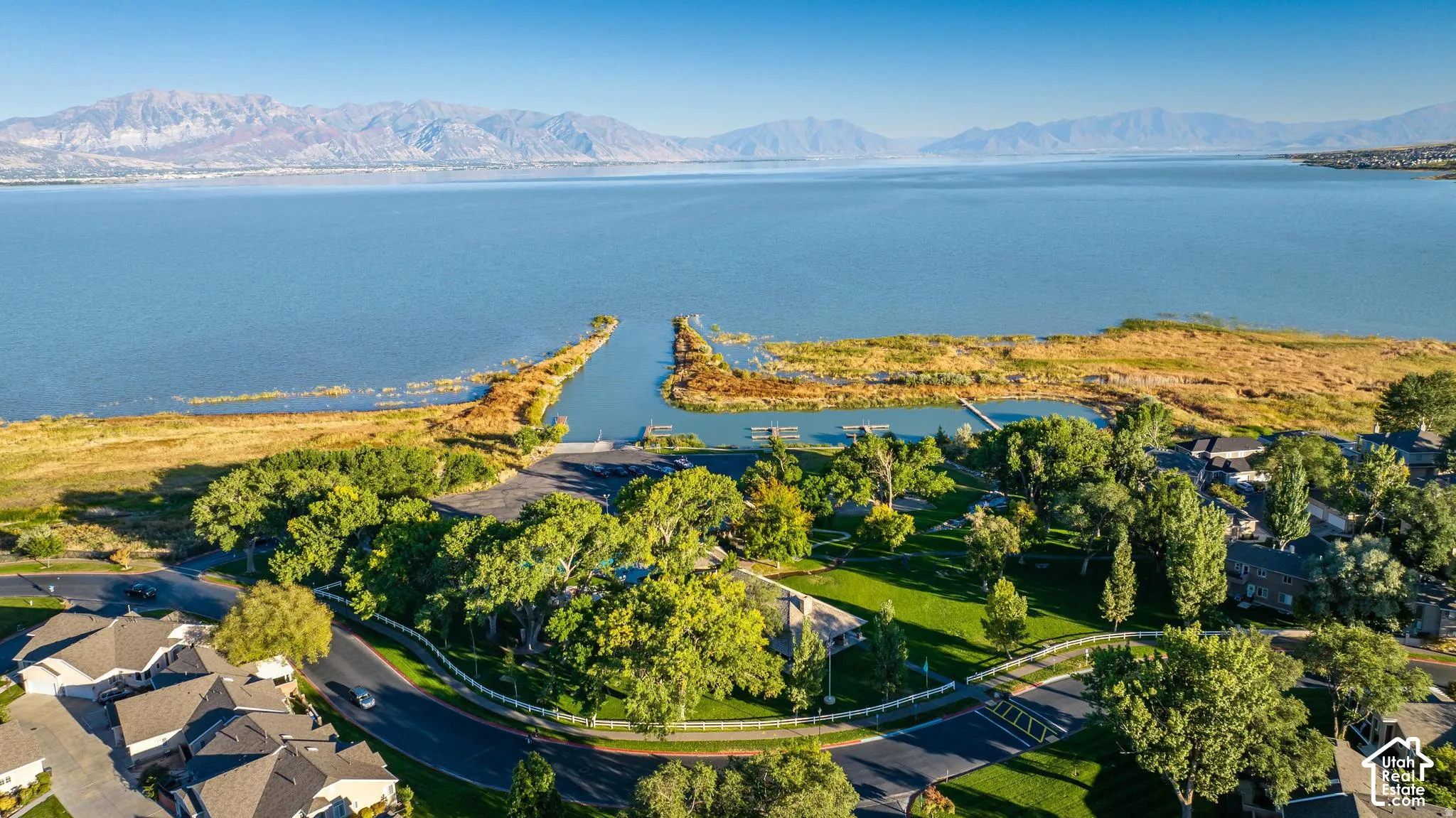 Expansive waterfront property featuring a boat launch, a dock, and mature trees, with a mountain backdrop