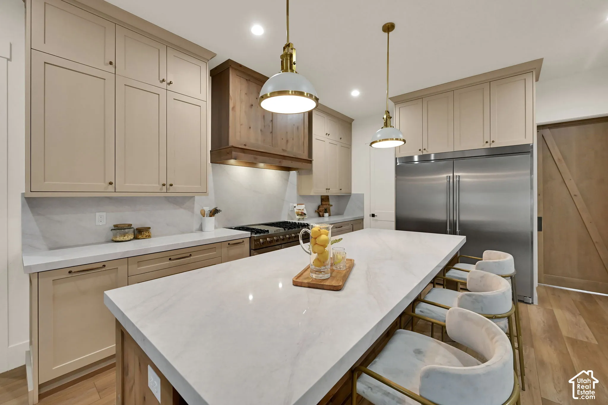 Gourmet kitchen featuring a large central island, stainless steel refrigerator, professional-grade range, wood-finish flooring, and recessed lighting
