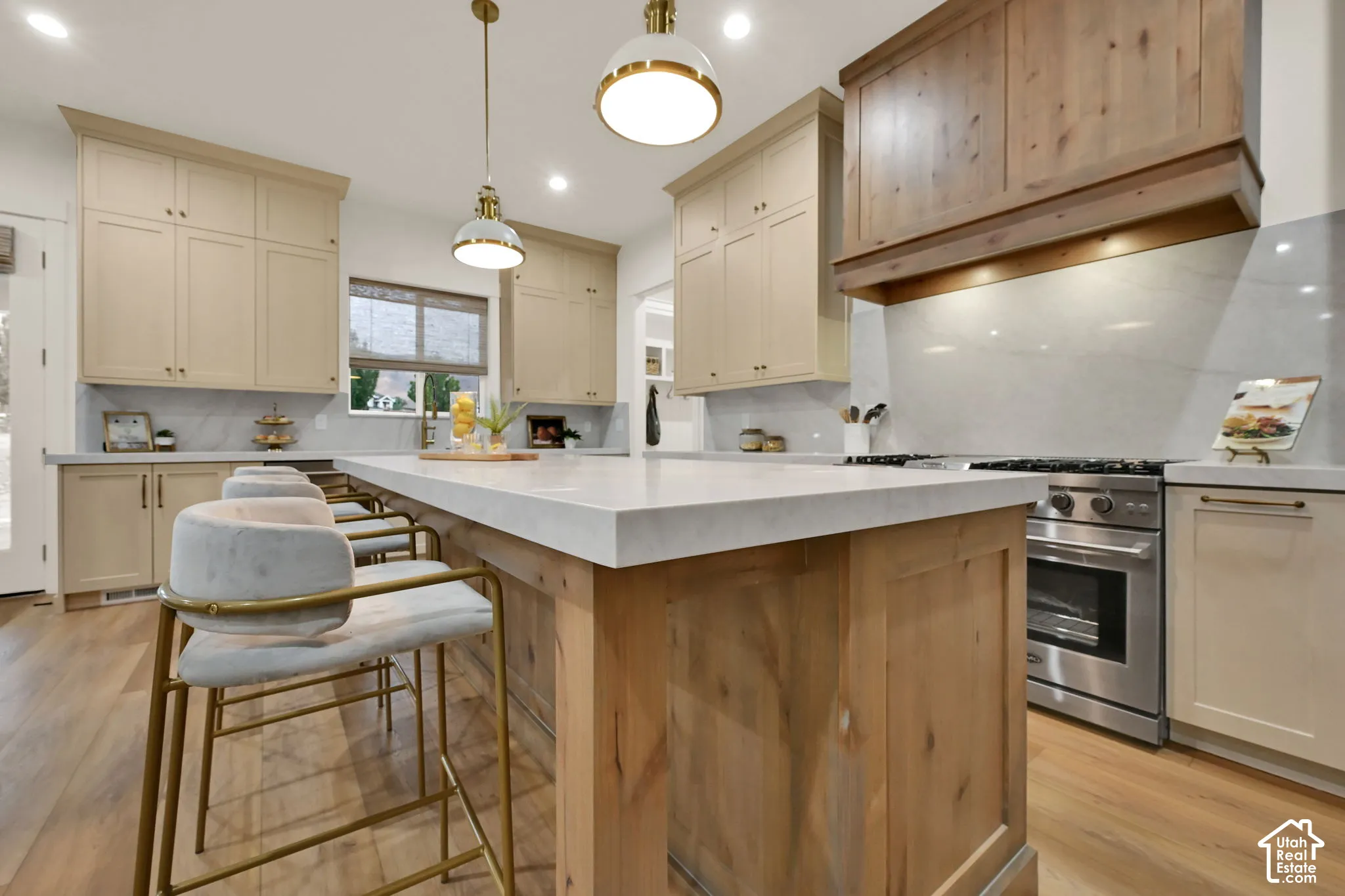Kitchen featuring a wood-finish island, light-toned cabinetry, stainless steel range, and stone countertops with matching backsplash