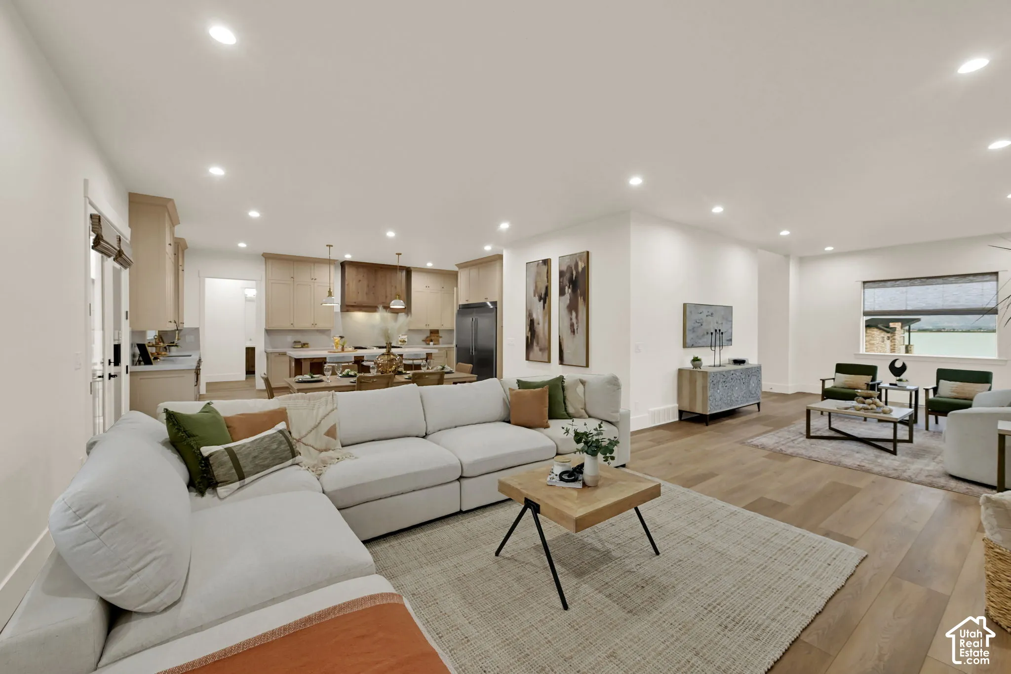 Open-concept living area with wood-finish flooring, recessed lighting, and a kitchen featuring light wood cabinetry