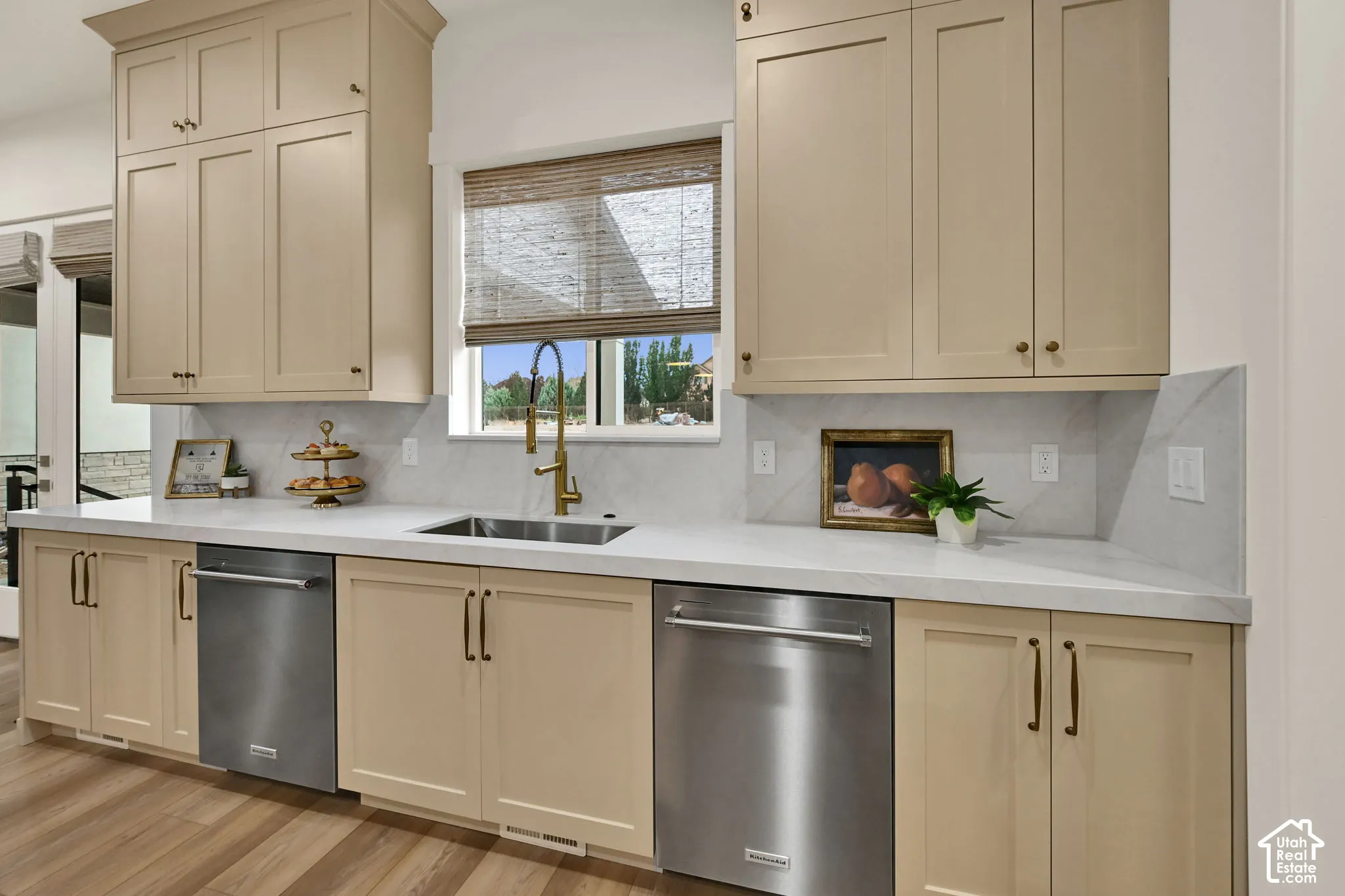Extensive upper and lower cabinetry, under-mount stainless steel sink with a high-arch faucet, integrated stainless steel dishwashers, and light-toned countertops