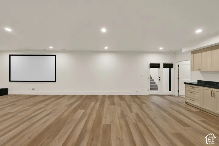 Spacious room featuring wood-finish flooring, recessed lighting, and a large projection screen