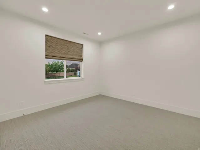 Recessed lighting, light gray carpet flooring, window with natural woven shade, white trim, and white walls