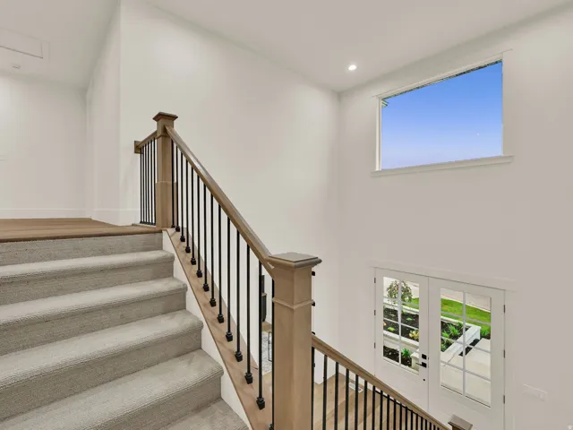 Carpeted staircase with wood-finish handrails and black metal balusters
