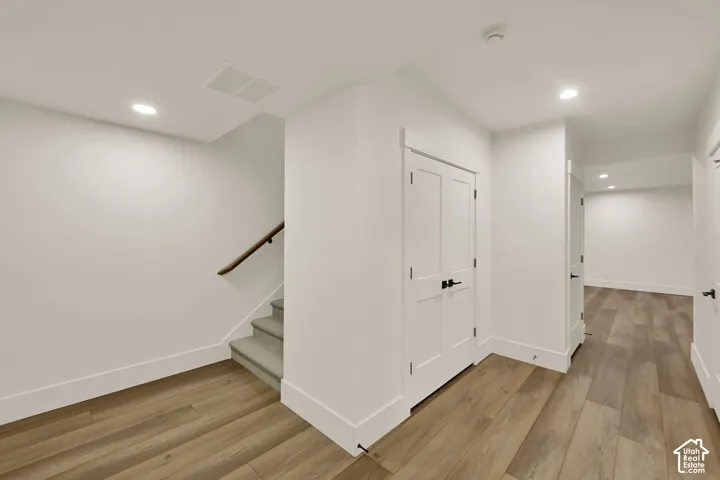 Wood-finish flooring with white trim and a carpeted staircase