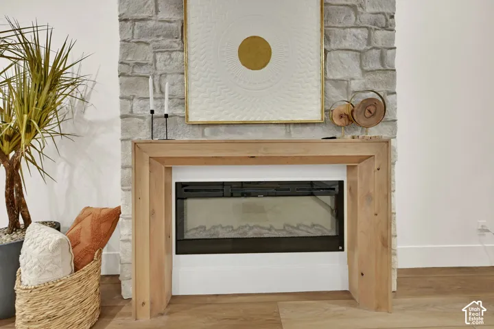 Stone accent wall featuring a built-in fireplace with a light wood mantle, set against light wood-finish flooring