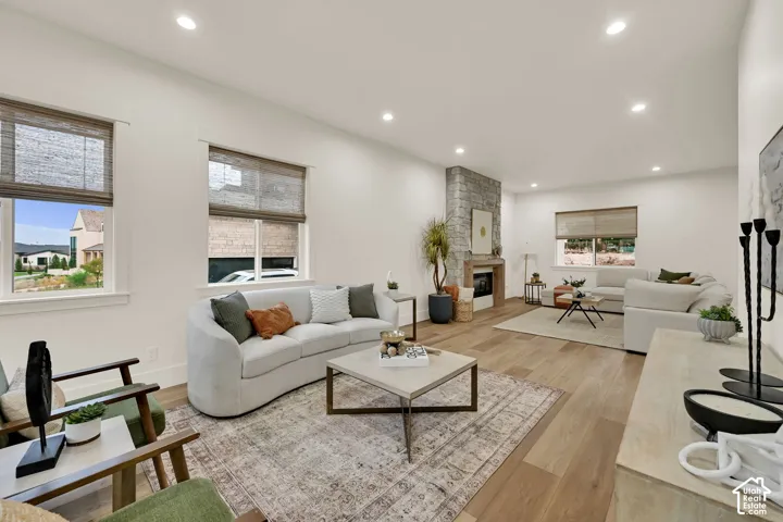 Wood-finish flooring, recessed lighting, and a stone-clad fireplace with a wood mantel