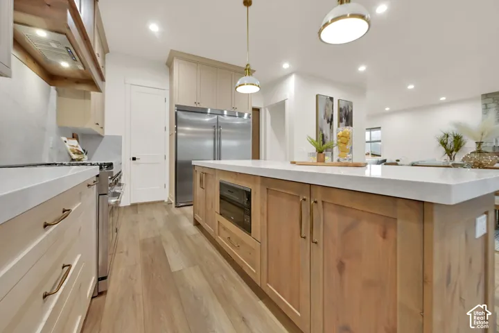 Gourmet kitchen featuring wood-finish flooring, two-tone cabinetry, stainless steel appliances, and a central island with integrated microwave