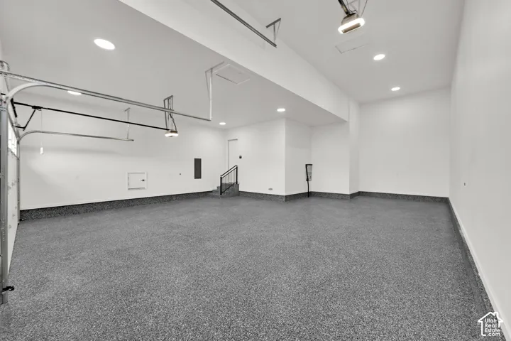 Spacious garage featuring a durable speckled epoxy floor, recessed lighting, and a utility access door