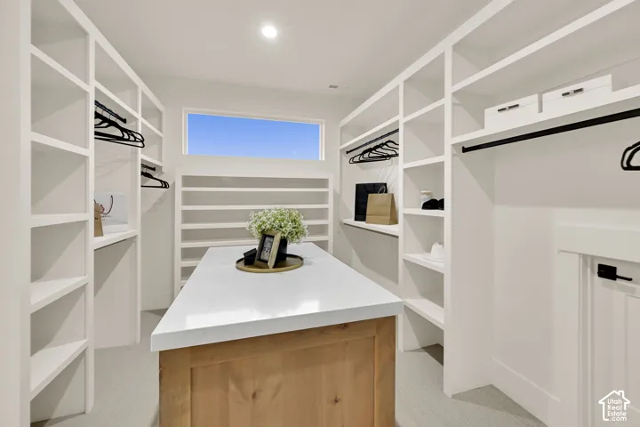 Custom closet system with extensive built-in shelving, hanging rods, and a central island featuring a light-toned countertop