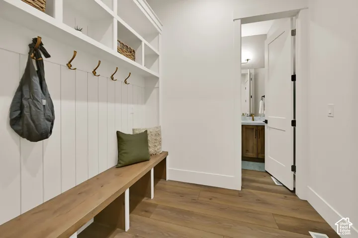 Built-in shelving with storage cubbies, wall-mounted coat hooks, wood-finish bench seating, wood-finish flooring, and white interior doors