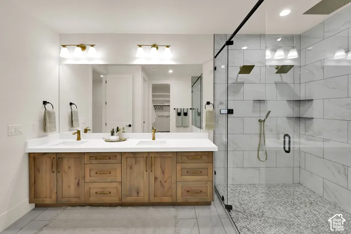 Dual vanity with wood-finish cabinetry, white countertops, and brass fixtures