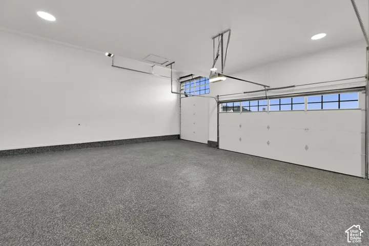 Epoxy-coated flooring, two overhead garage doors with window panels, recessed lighting, and white finished walls