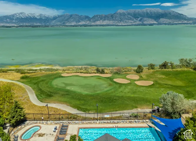 Championship golf course with manicured fairways and strategically placed bunkers overlooking turquoise waters and snow-capped mountain range