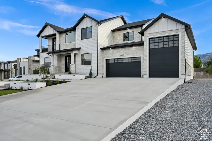 Contemporary exterior with stone and siding, featuring a covered entry, an upper-level balcony, and multiple large windows