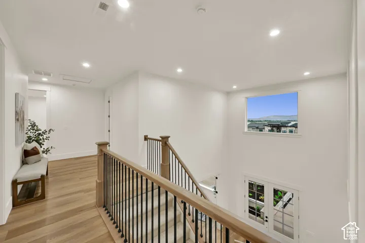 Upper-level landing with wood-finish flooring, recessed lighting, and a window with a distant mountain backdrop