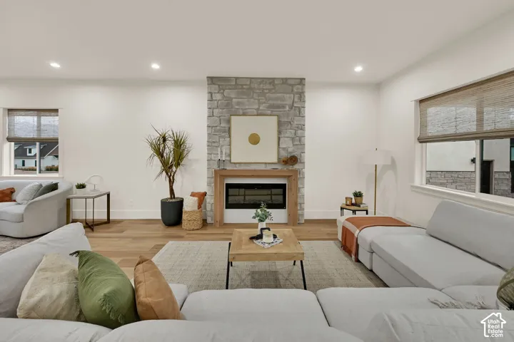 Stone-clad fireplace with wood surround, recessed lighting, wood-finish flooring, and multiple windows