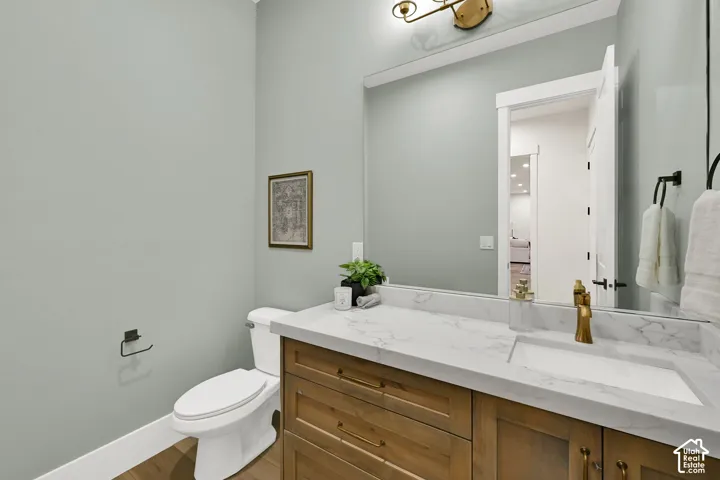 Wood-finish vanity with an integrated rectangular sink, stone-finish countertop, and a wall-mounted mirror