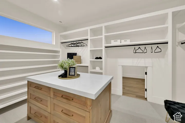 Custom built-in shelving, wood-finish center island with a light-toned countertop, integrated hanging rods, and a high horizontal window
