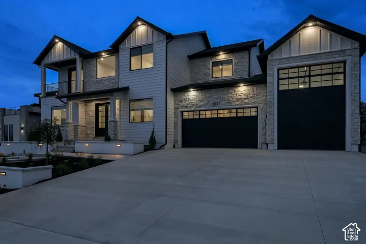 Modern exterior featuring stone and horizontal siding, an attached garage with two black doors, and a concrete driveway