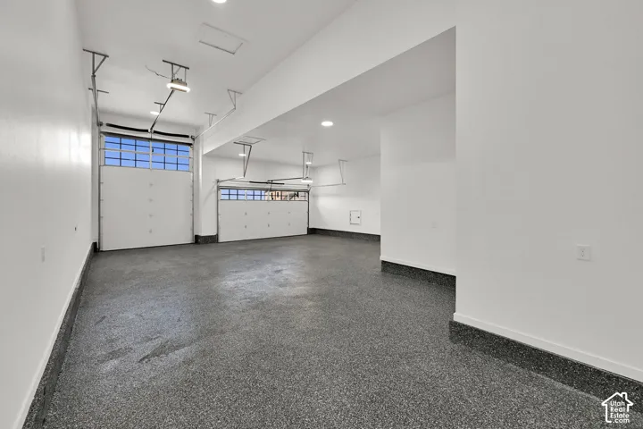Two garage doors with upper window panels, recessed lighting, white walls, and a speckled epoxy floor