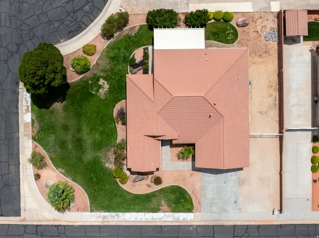 Terracotta-style roof, expansive green lawn, mature landscaping, concrete driveway, and side yard